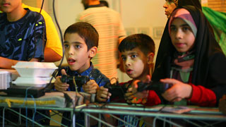 بچه‌های محله در حال تجربه‌ی یک بازی رایانه‌ای هشت نفره